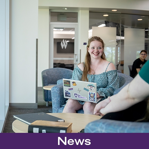 Person smiling, holding a laptop.